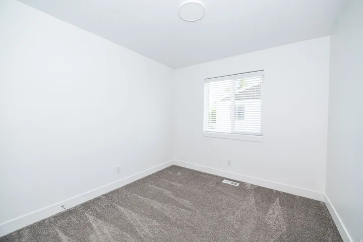 Room featuring grey carpeting, white baseboards, and a window with blinds