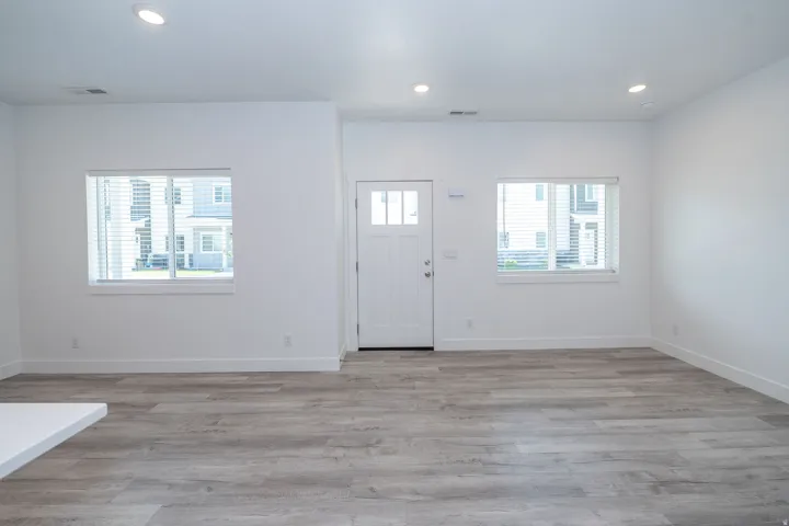 Entryway featuring a white paneled door with glass inserts, flanked by two windows with blinds