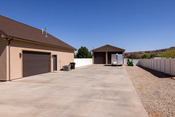 Expansive concrete driveway leading to a two-car garage and a detached two-door garage structure