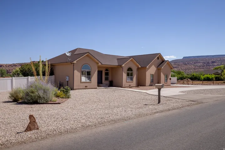 Stucco exterior with arched windows, a multi-gabled roof, and a gravel front yard