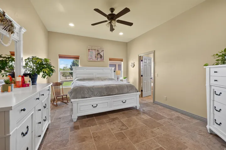 Spacious room featuring vaulted ceilings, recessed lighting, a ceiling fan, and large format stone tile flooring
