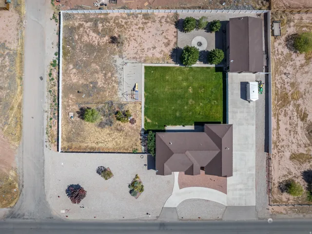 Expansive property featuring a brown-roofed residence, a separate accessory structure, a large manicured lawn, a concrete driveway, and a decorative gravel fire pit area