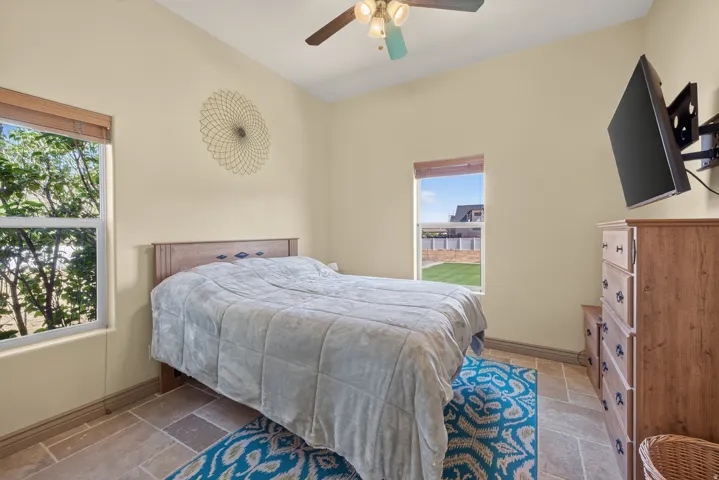 Spacious room featuring vaulted ceilings, a ceiling fan with integrated lighting, and two large windows offering ample natural light