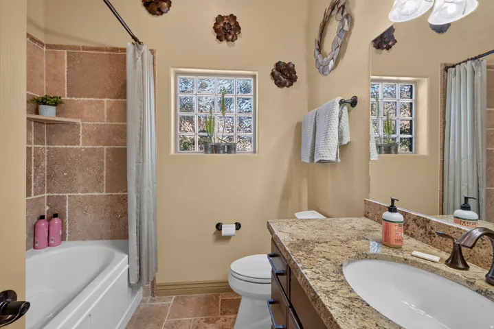 Bathroom featuring a built-in tub with a stone-tiled surround and an integrated shelf