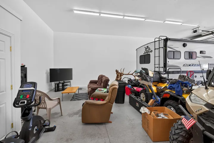 Spacious garage area featuring a concrete floor, white walls, and overhead fluorescent lighting