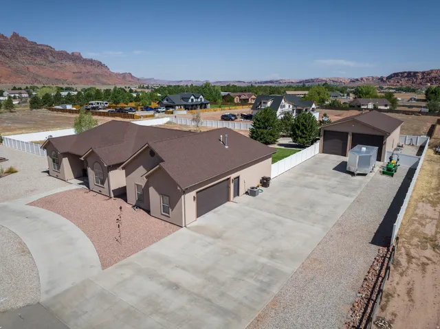 Stucco exterior residence featuring an attached garage and a detached multi-bay garage
