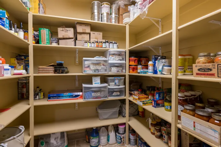 Walk-in pantry featuring extensive built-in shelving, durable wood-finish construction, and ample storage capacity