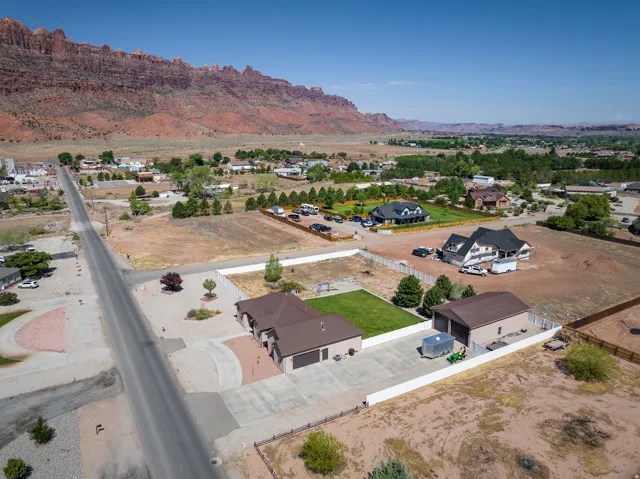 Expansive property featuring a paved driveway, detached garage structure, and a large grassy area