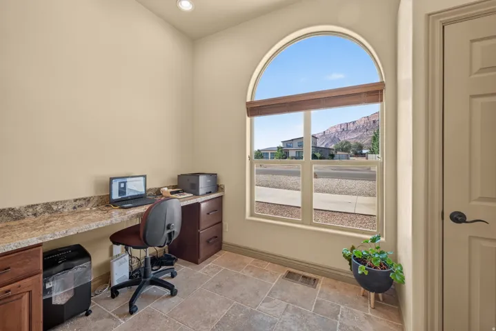 Room featuring a large arched window with horizontal blinds, providing natural light