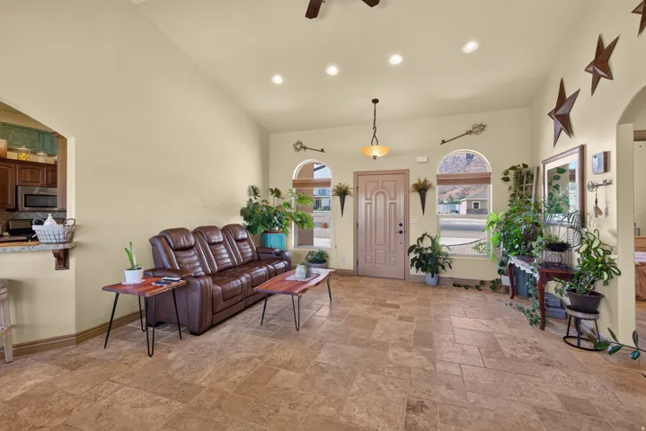 Spacious living area featuring neutral-toned walls, tile flooring, and a vaulted ceiling