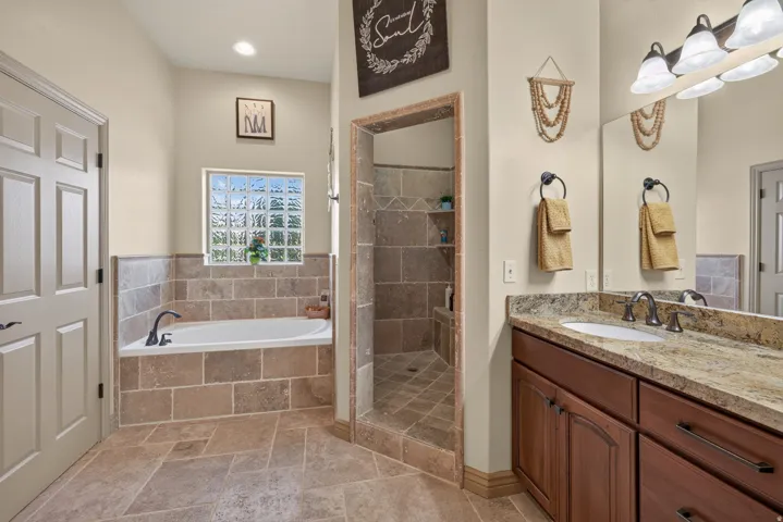 Bathroom featuring a built-in soaking tub with a tiled surround, a glass block window, and a separate tiled shower