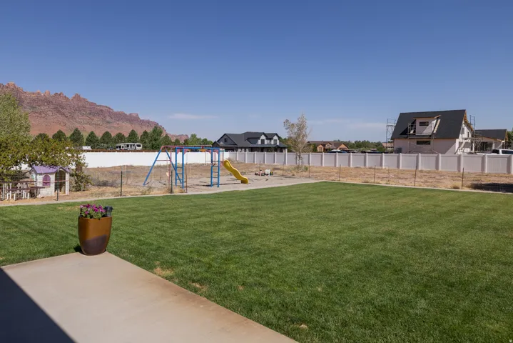 Expansive grassy yard with mountain backdrop, concrete patio, and privacy fencing