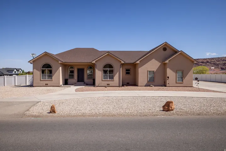 Stucco exterior with arched windows, a brown shingle roof, and an attached driveway