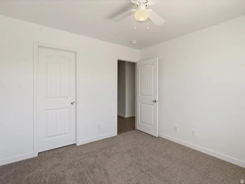 Room featuring plush carpet flooring, white painted walls, and a ceiling fan with integrated lighting