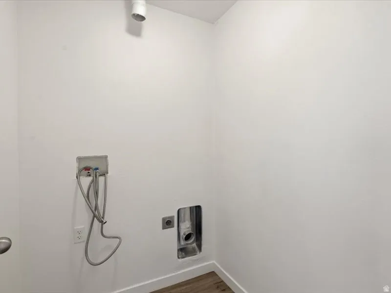 Dedicated utility space featuring laundry hookups, a dryer vent, and wood-finish flooring