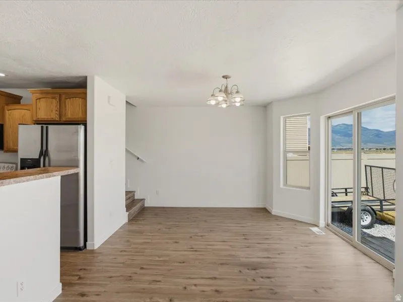Open-concept living area featuring wood-finish flooring, a contemporary ceiling light fixture, and white wall finishes
