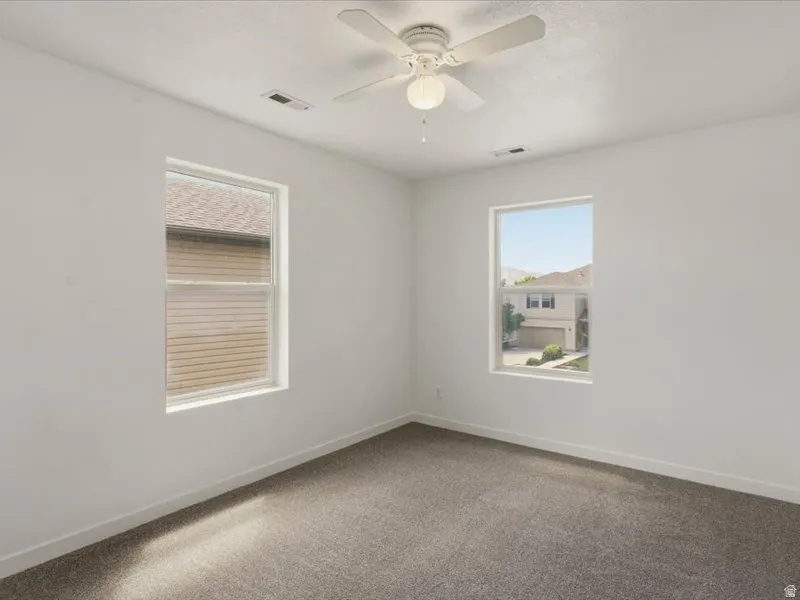 Room featuring neutral-toned carpet, white walls, and a ceiling fan with integrated lighting