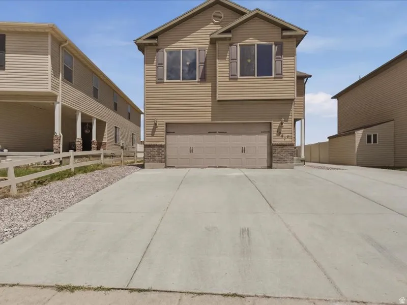 Two-story residence featuring light-colored siding and a two-car garage