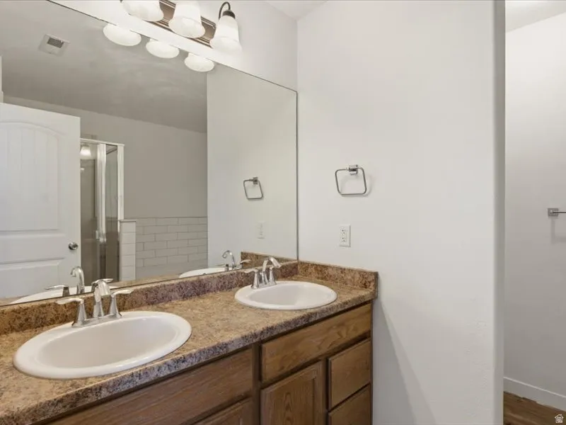 Dual undermount sinks set in a stone-finish countertop with a wood-finish vanity cabinet