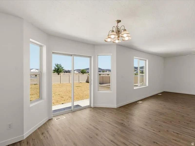 Expansive interior room featuring wood-finish flooring, a contemporary ceiling light fixture, and multiple windows