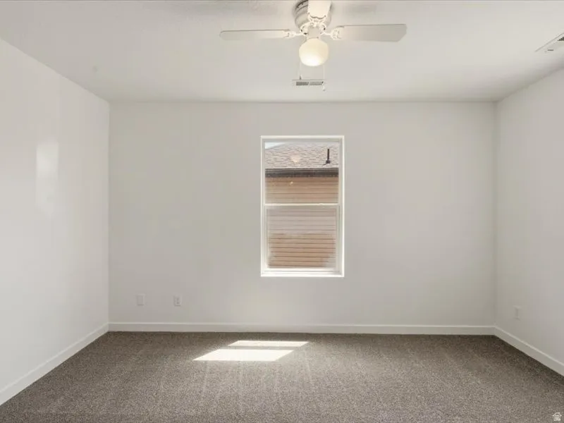 Neutral tone walls with white trim, a single window, and a ceiling fan with integrated lighting