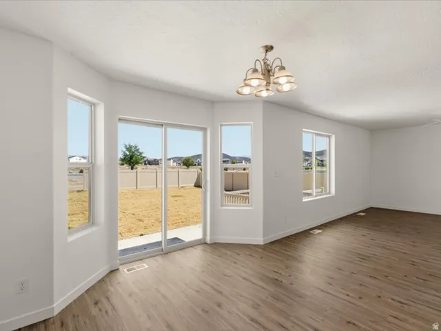 Expansive interior room featuring wood-finish flooring, a contemporary ceiling light fixture, and multiple windows