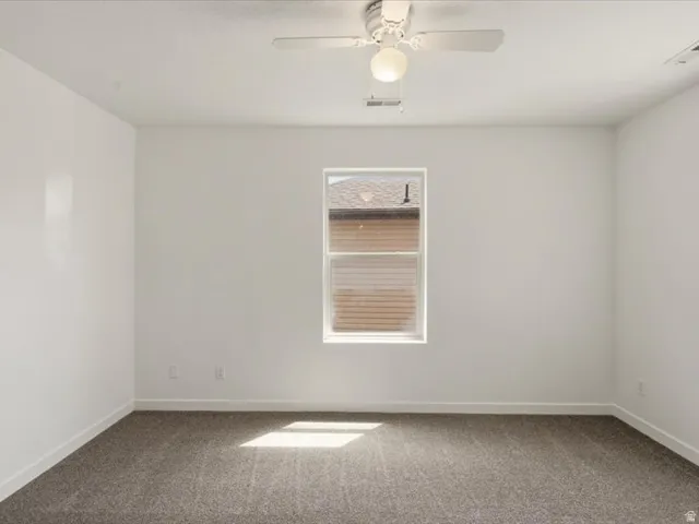 Neutral tone walls with white trim, a single window, and a ceiling fan with integrated lighting
