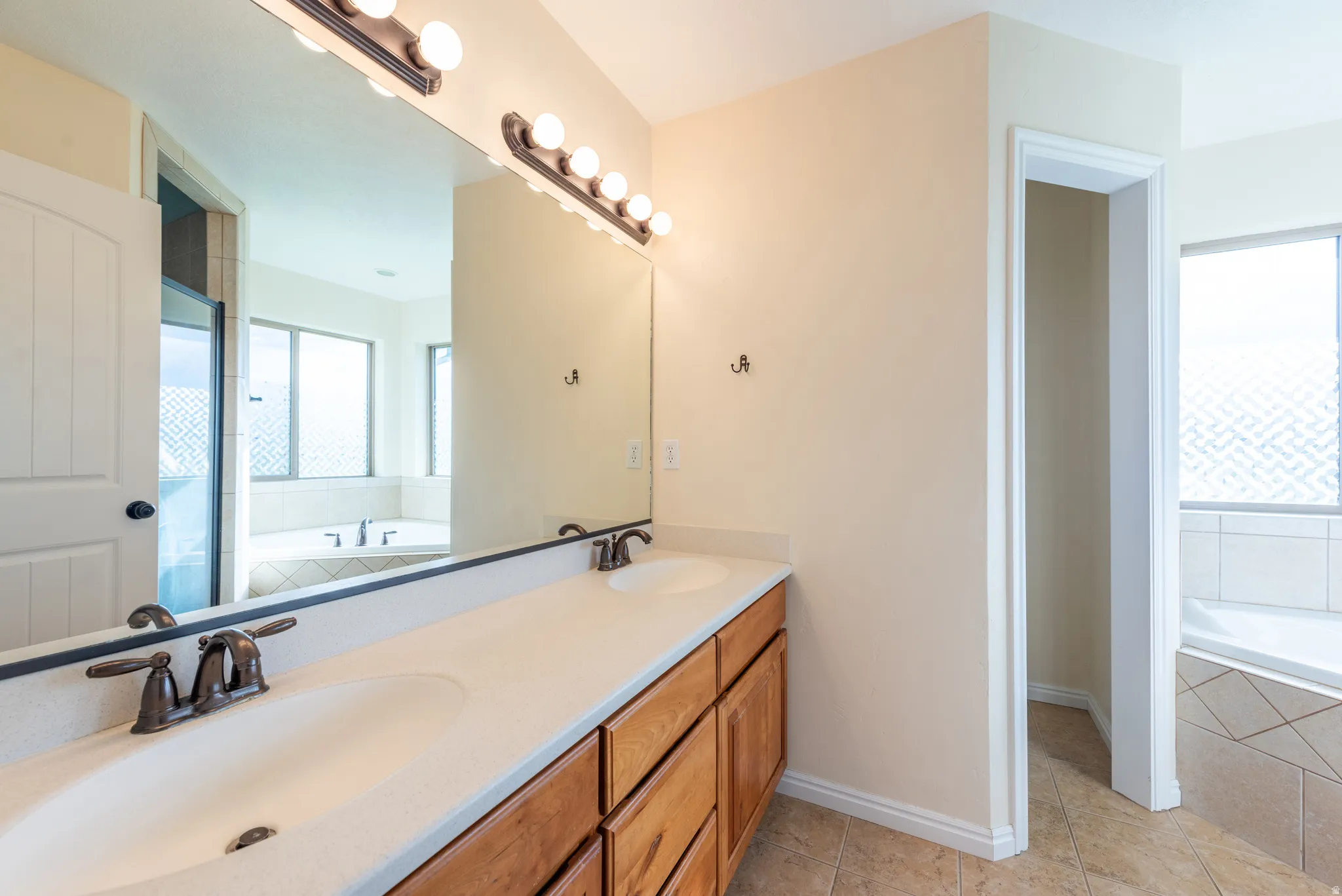 Spacious bathroom featuring a double vanity with ample counter space, rich wood cabinetry, and bronze-finish fixtures