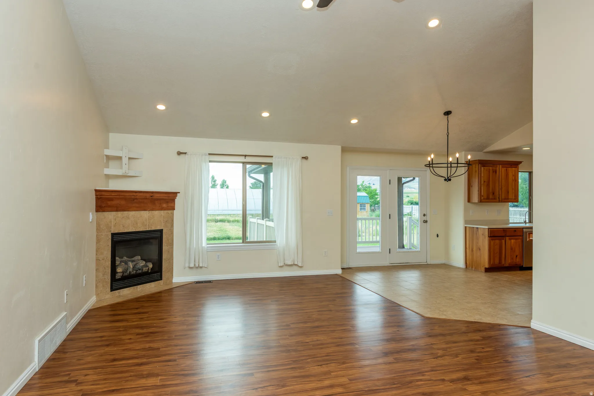 Spacious room featuring wood-finish flooring, a corner fireplace with a tile surround and wooden mantel, and recessed lighting