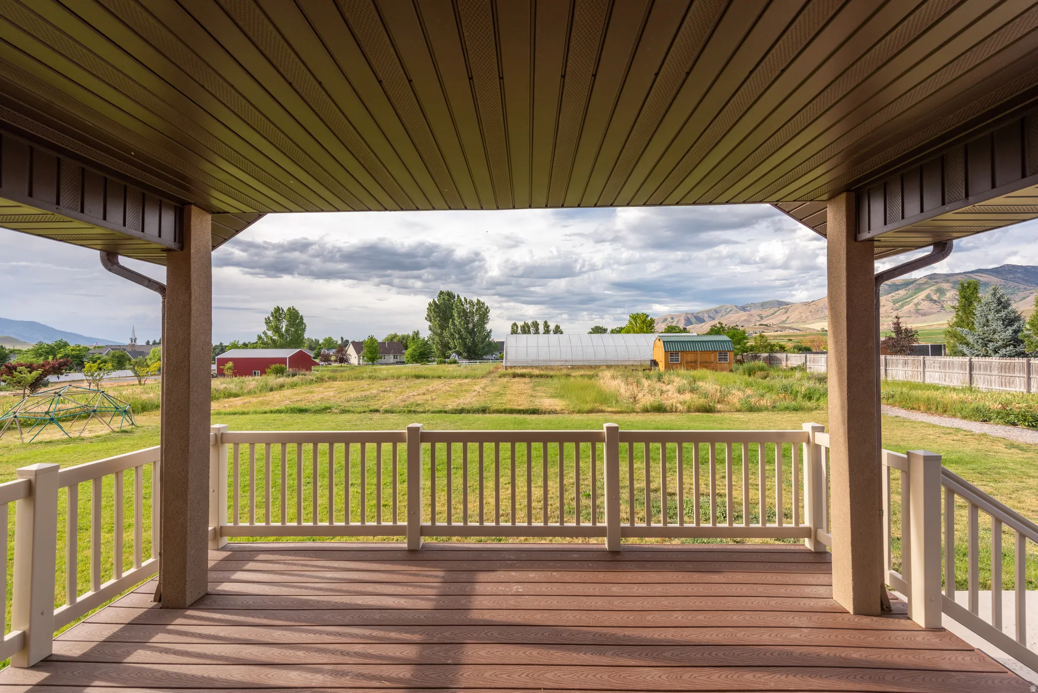Covered porch featuring wood-finish decking and white baluster railing