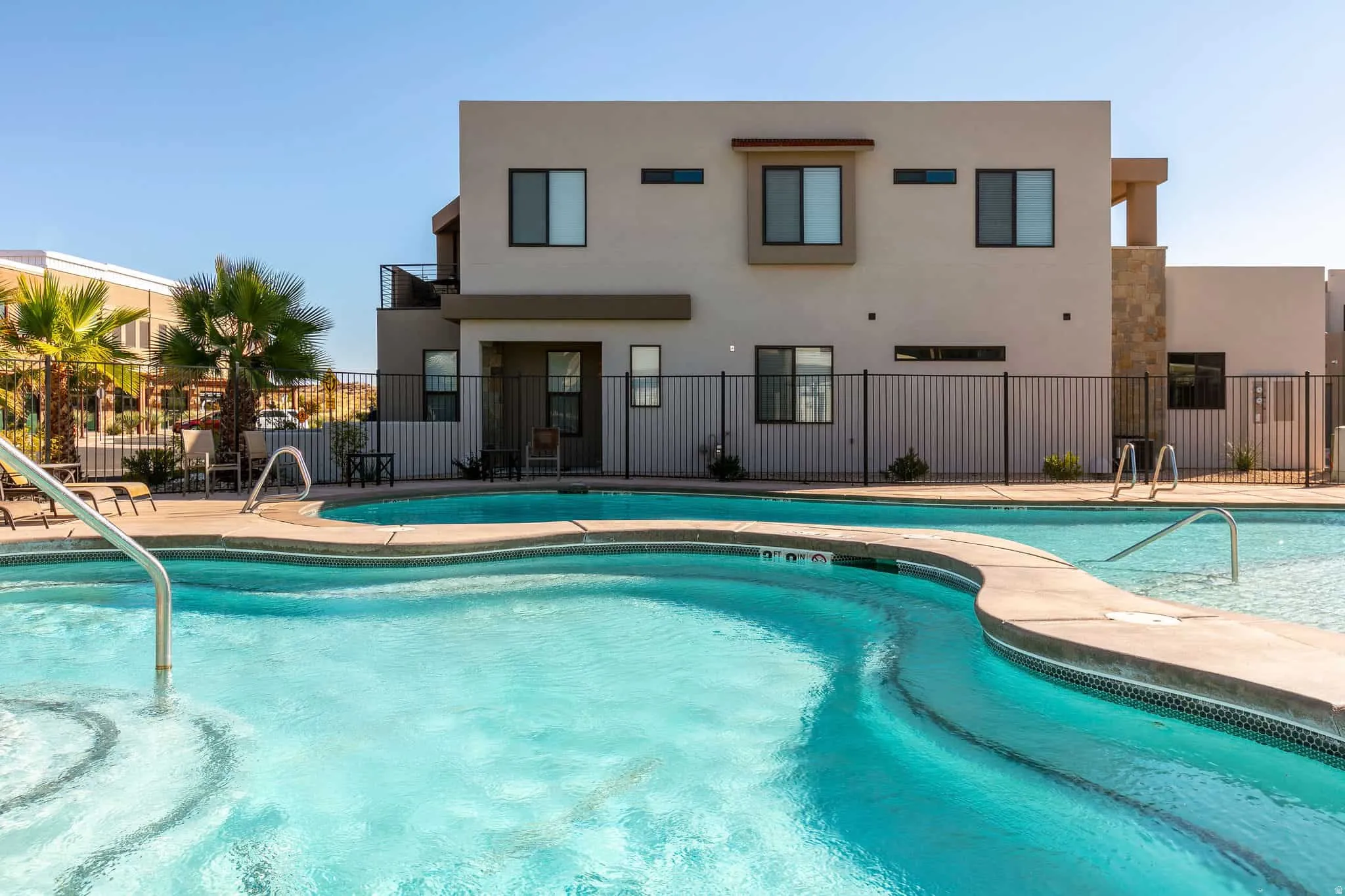 Curved swimming pool with integrated spa and concrete coping