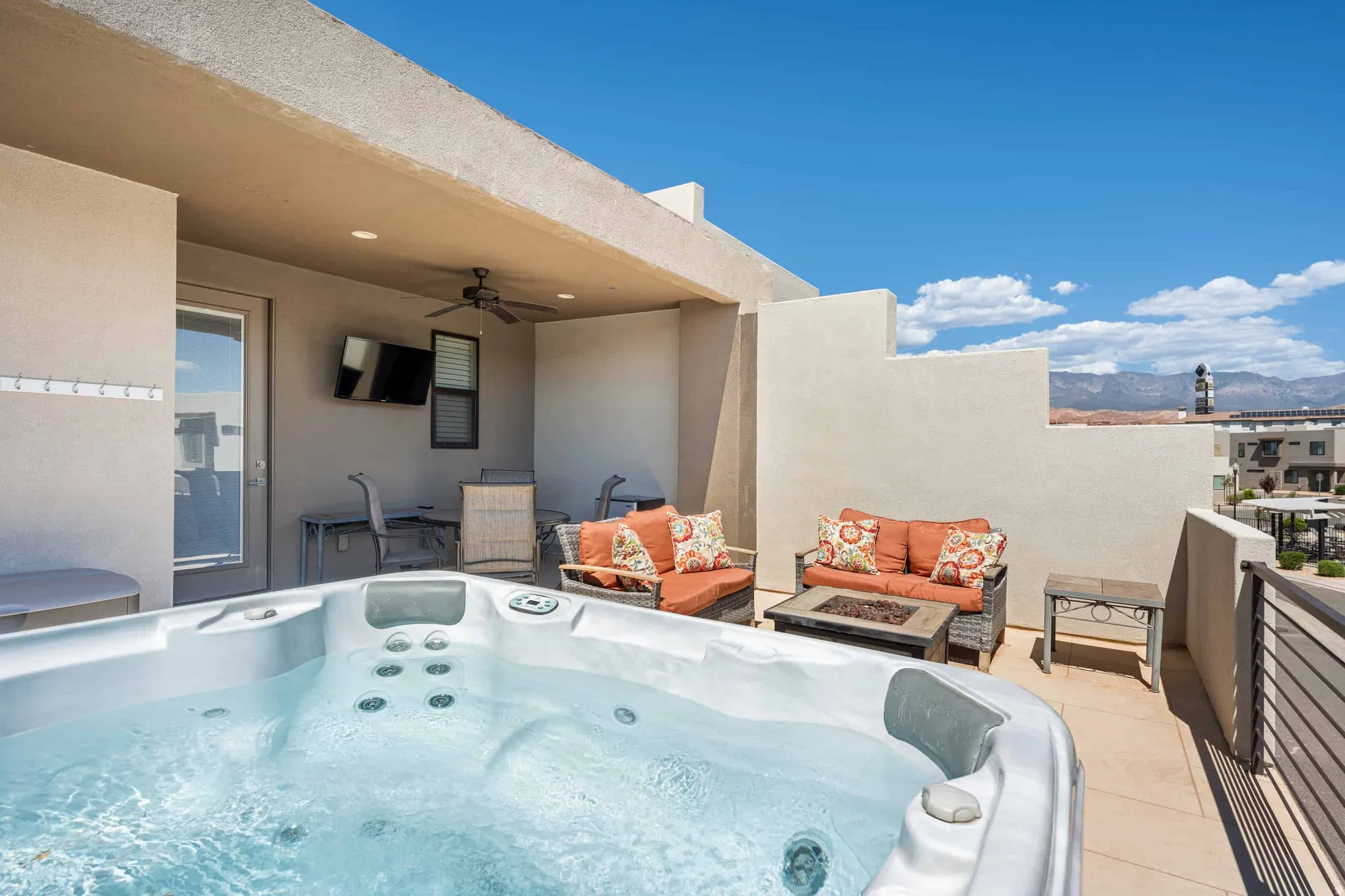 Rooftop deck featuring a built-in hot tub, covered patio area, ceiling fan, and mountain backdrop