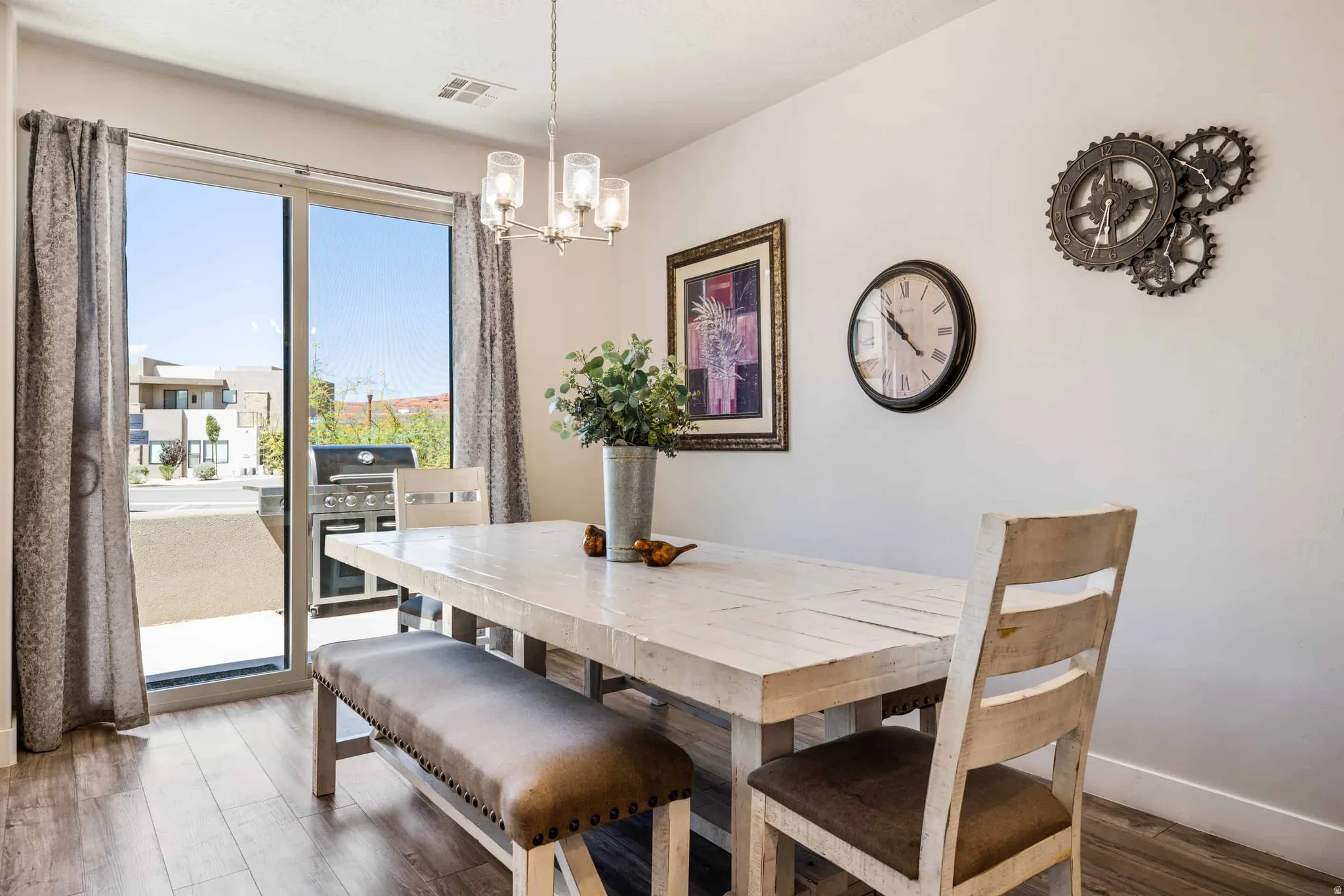 Dining area featuring wood-finish flooring, a contemporary chandelier, and a sliding glass door providing access to an outdoor patio space