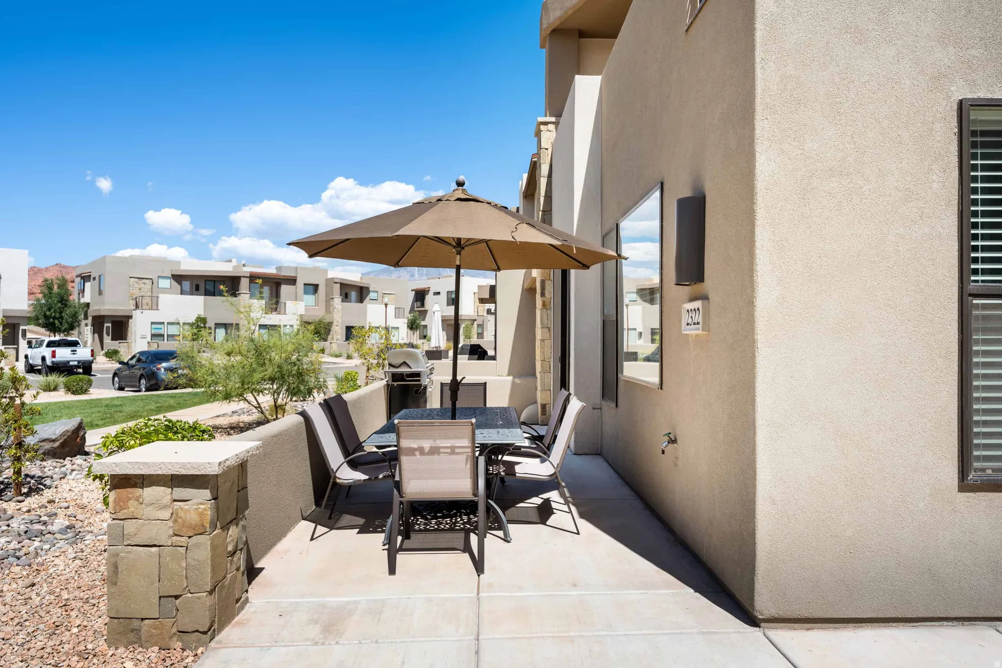 Exterior concrete patio featuring a low stone privacy wall and stucco-finished architecture