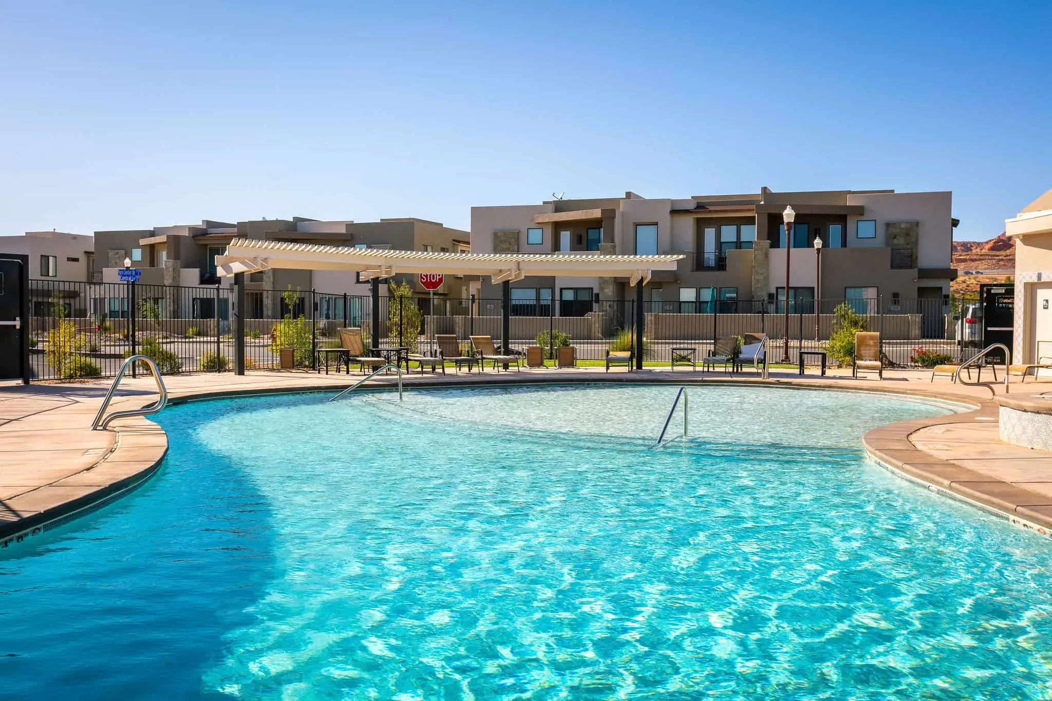 Curved swimming pool with integrated steps, surrounded by a light-colored concrete deck