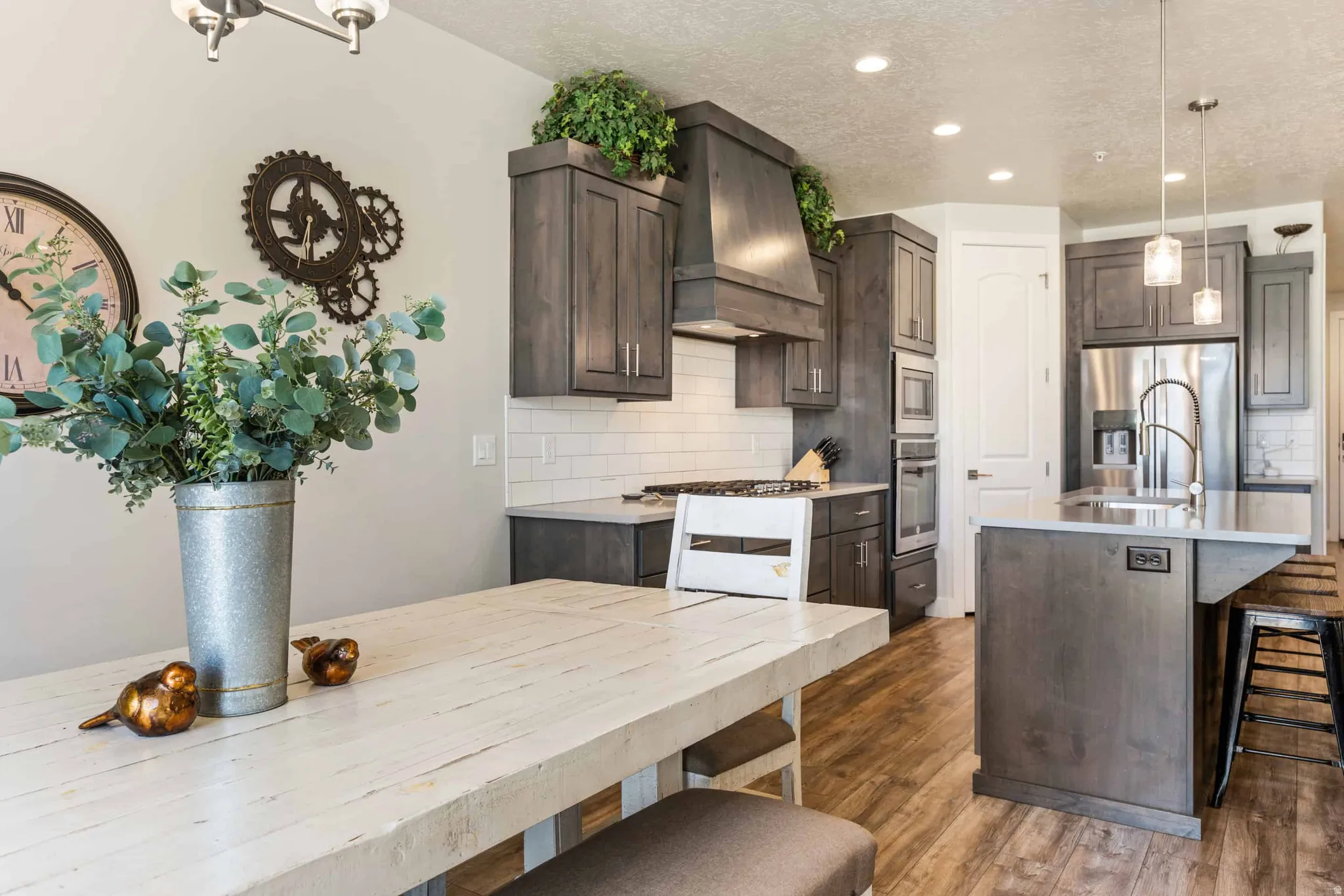 Kitchen featuring wood-finish flooring, white subway tile backsplash, stainless steel appliances, a center island with pendant lighting, and recessed ceiling lights