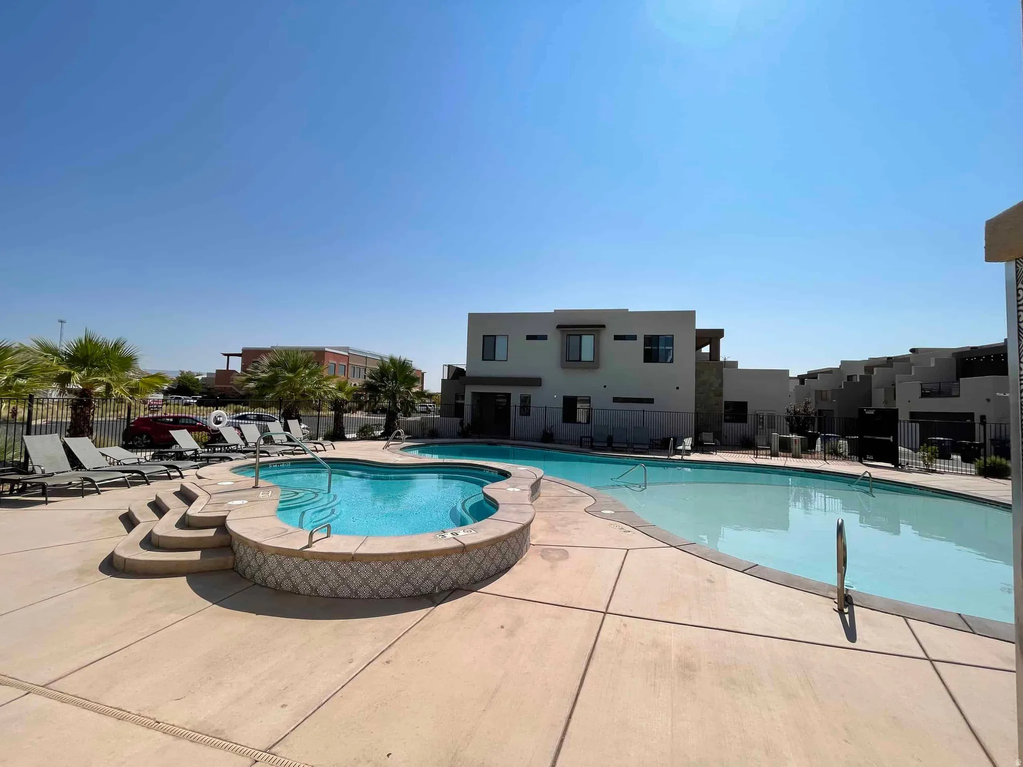 Lagoon-style swimming pool with an integrated spa, surrounded by a concrete patio and a variety of lounge seating