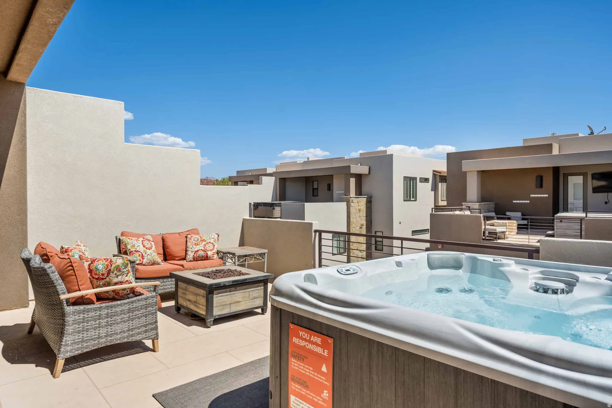 Private rooftop terrace featuring a built-in hot tub, perimeter walls, and a fire pit