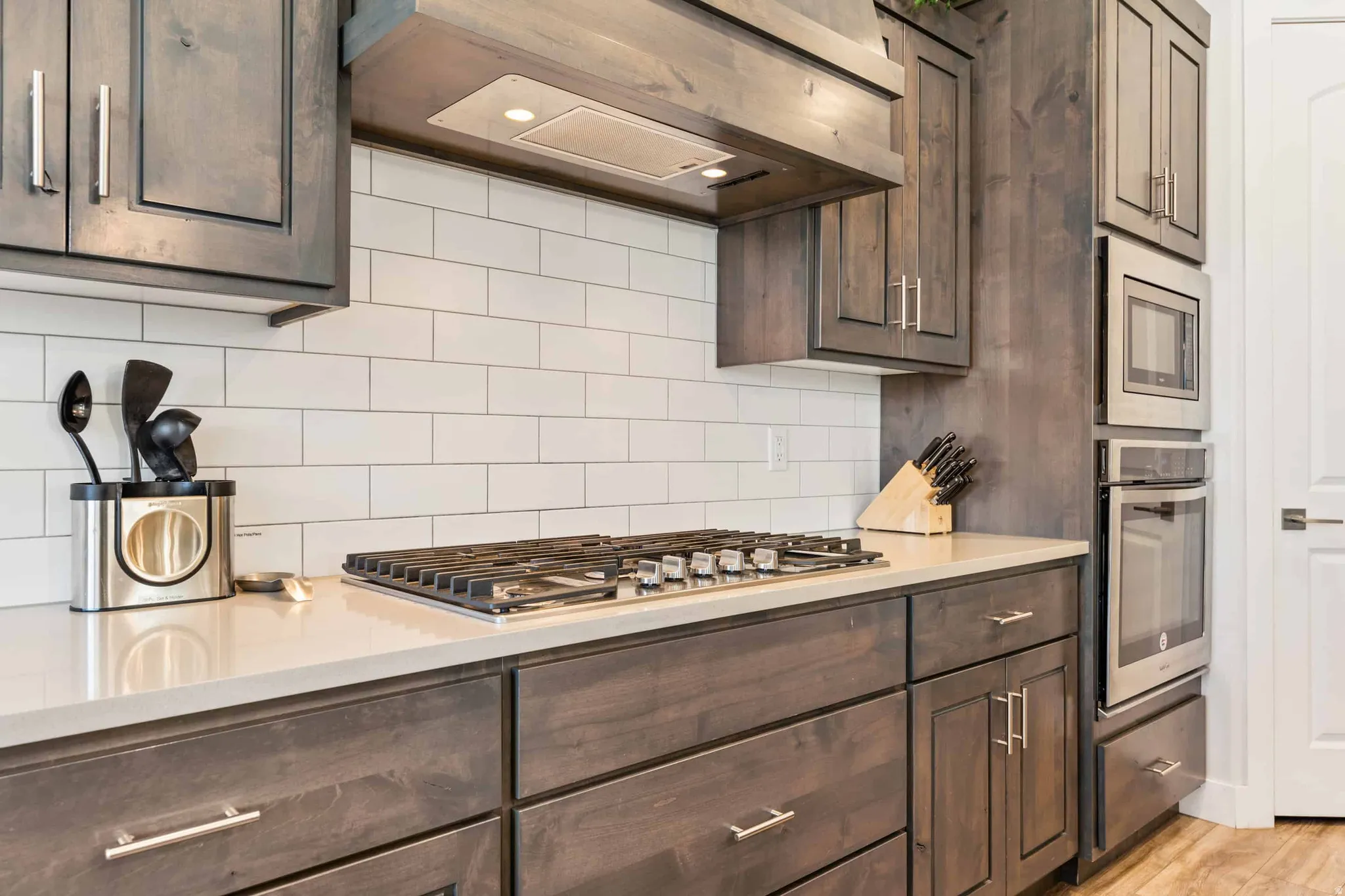 Kitchen featuring dark wood-finish cabinetry, light-toned countertops, and a white subway tile backsplash