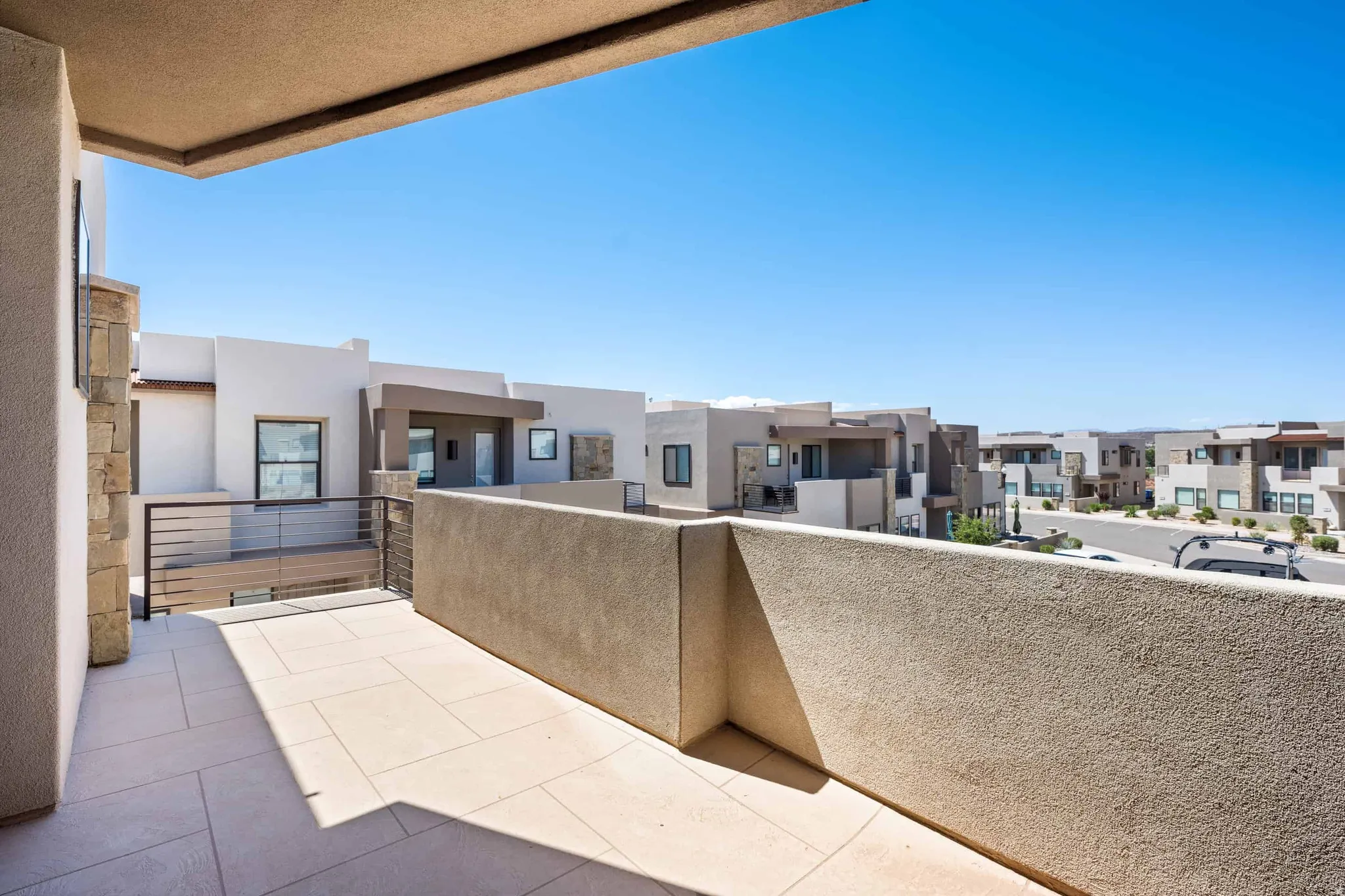Outdoor patio featuring light-colored square tile flooring and a concrete half-wall