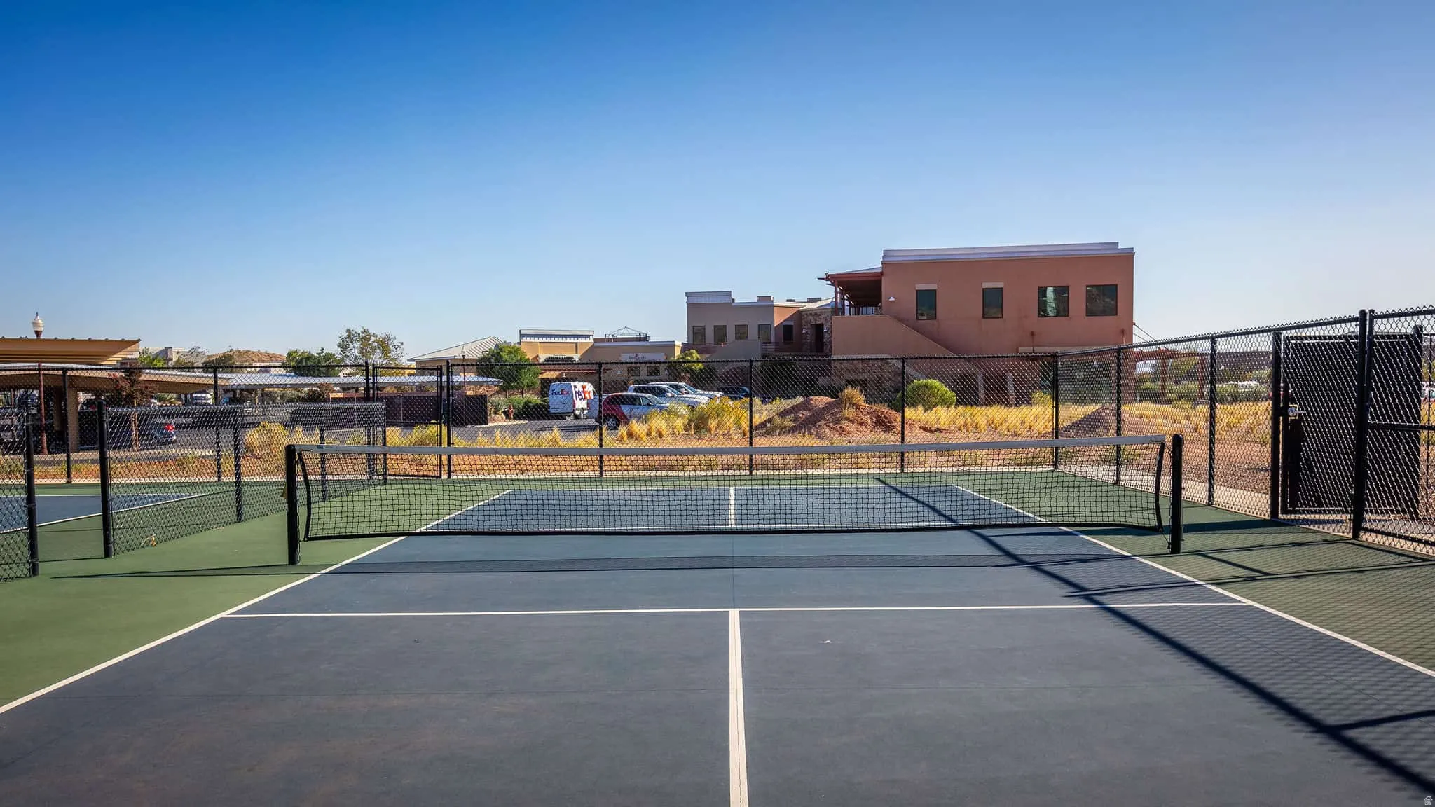 Regulation-size pickleball court with a blue and green playing surface, surrounded by black chain-link fencing