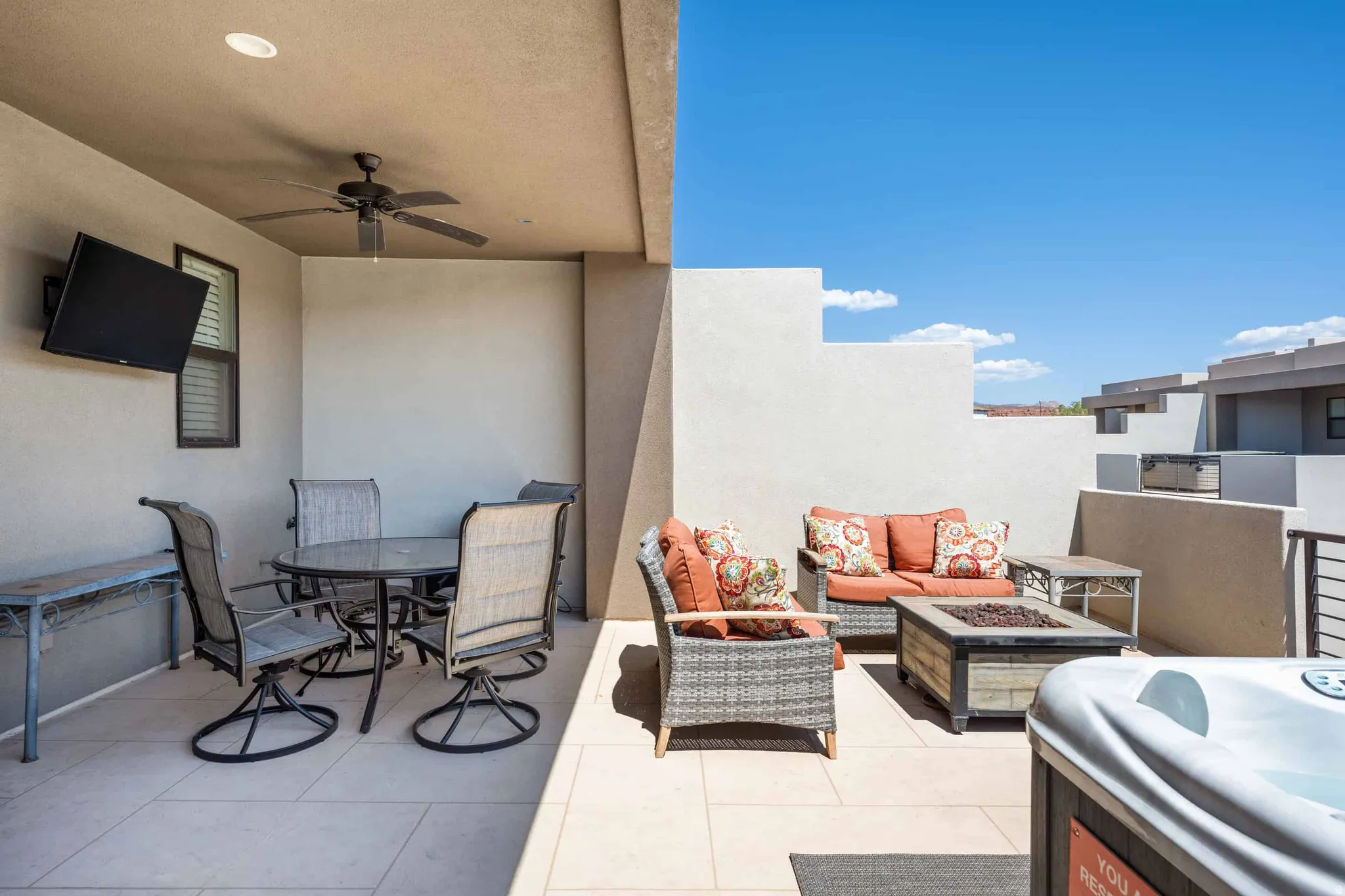 Expansive outdoor patio featuring light-toned tile flooring, a built-in ceiling fan, and a mounted flat-screen television