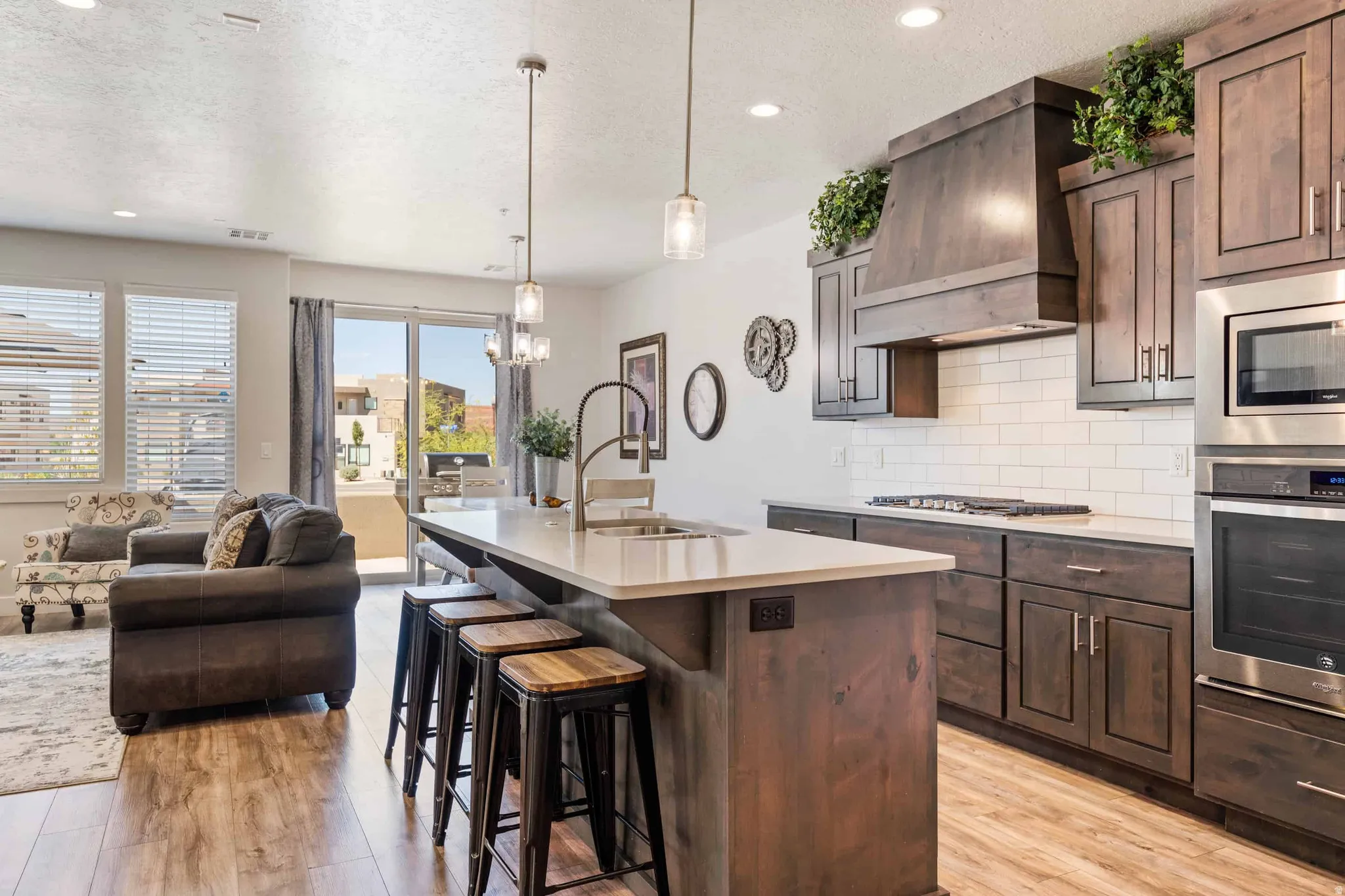 Modern kitchen featuring dark wood-finish cabinetry, stainless steel appliances, a subway tile backsplash, and a large island with seating