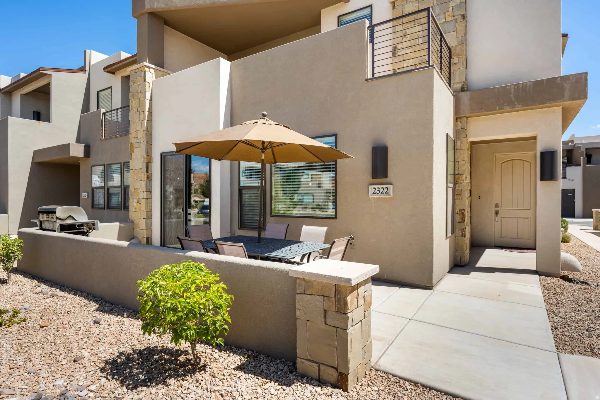 Contemporary stucco exterior with stone accents and a private patio