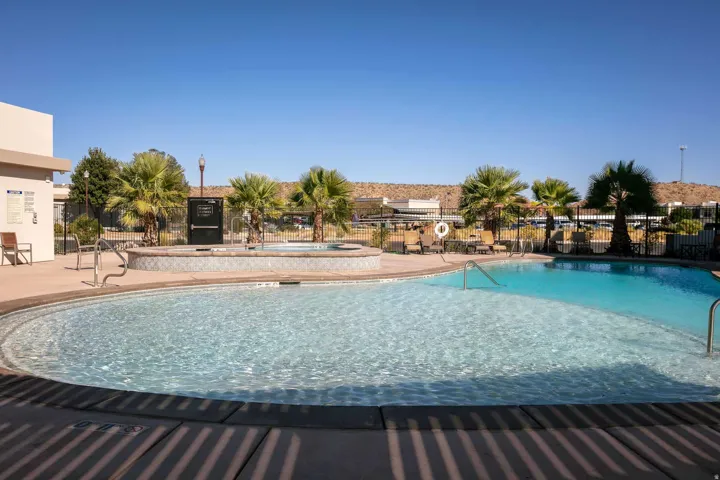 Curved swimming pool with an integrated spa, surrounded by concrete decking