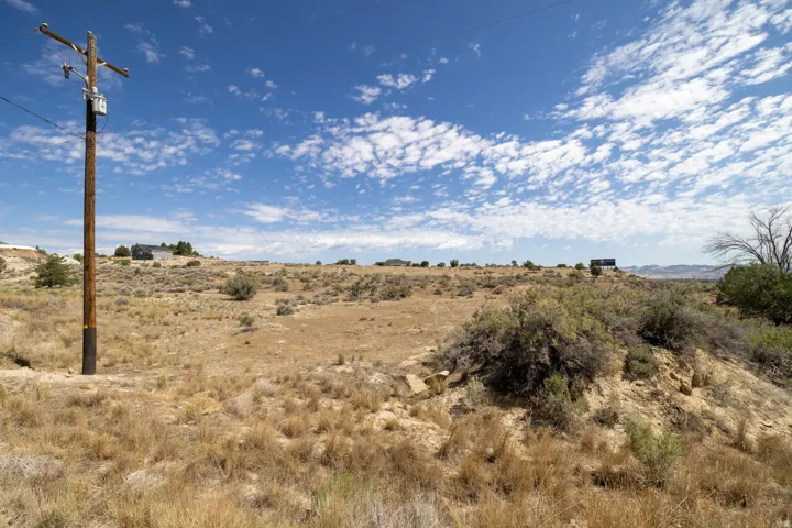 Expansive undeveloped land featuring natural desert landscaping and distant residential structures
