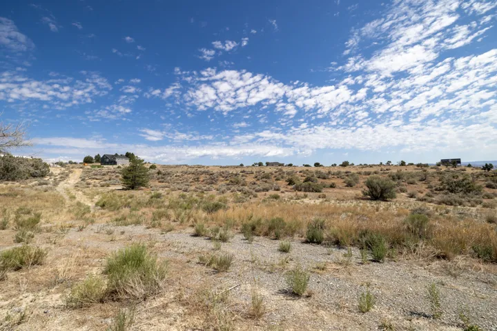 Expansive undeveloped land featuring natural desert landscaping, varied topography, and distant structures under a vibrant sky