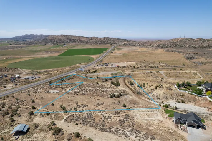 Expansive undeveloped lot featuring a natural desert landscape, bordered by a paved road