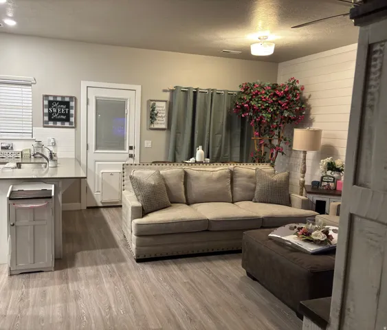 Open-concept living area featuring wood-finish flooring, a white shiplap accent wall, and recessed ceiling lighting