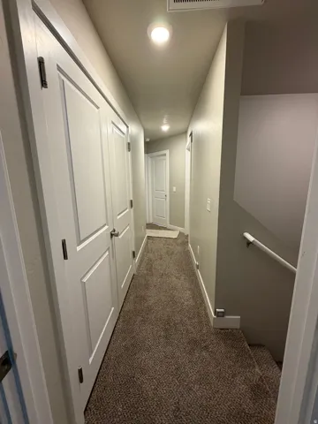 Hallway with recessed lighting, neutral wall paint, white trim, and brown carpet flooring